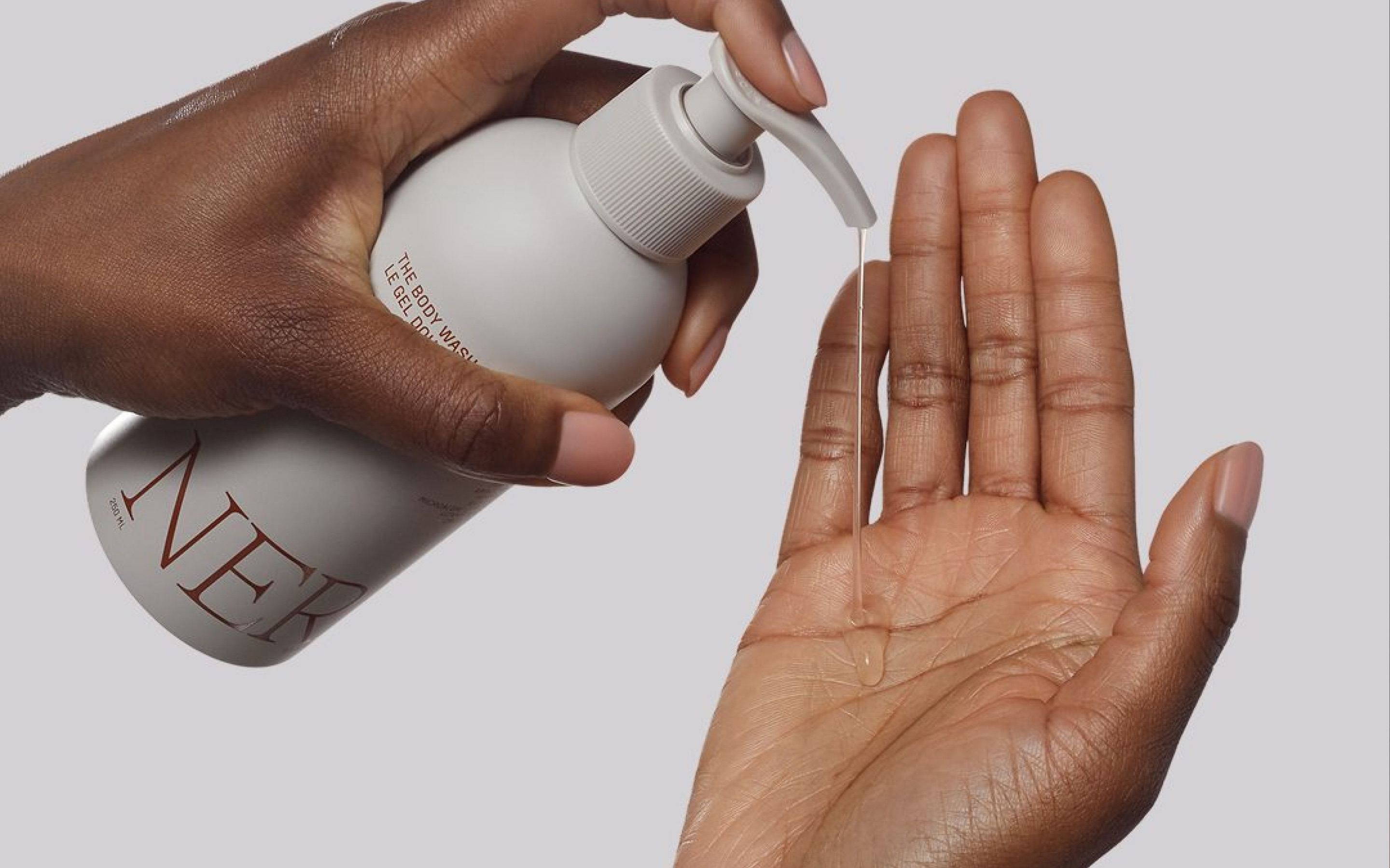 Nerra body wash being dispensed onto a hand against a neutral background