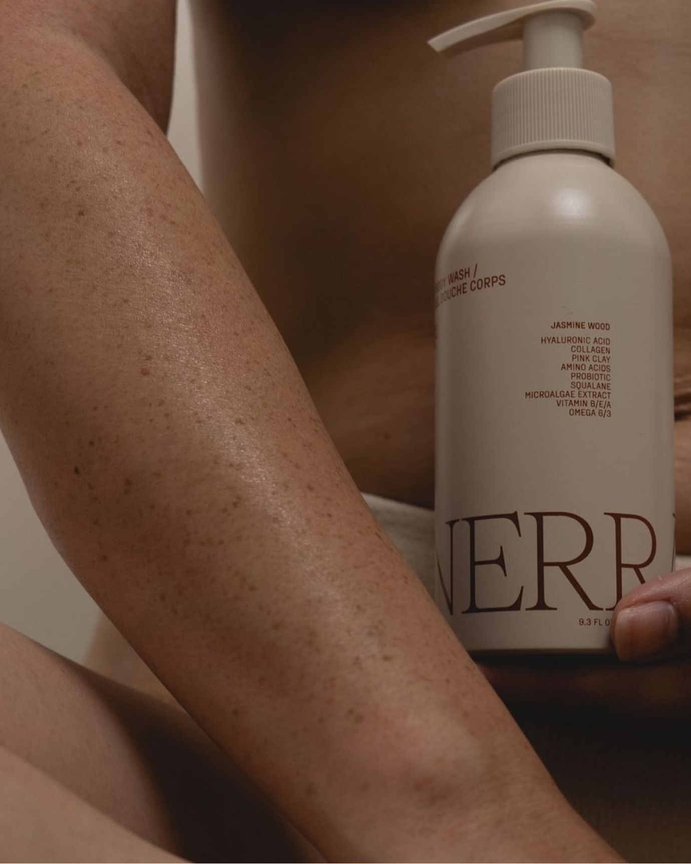 Nerra body lotion bottle held against a woman's legs
